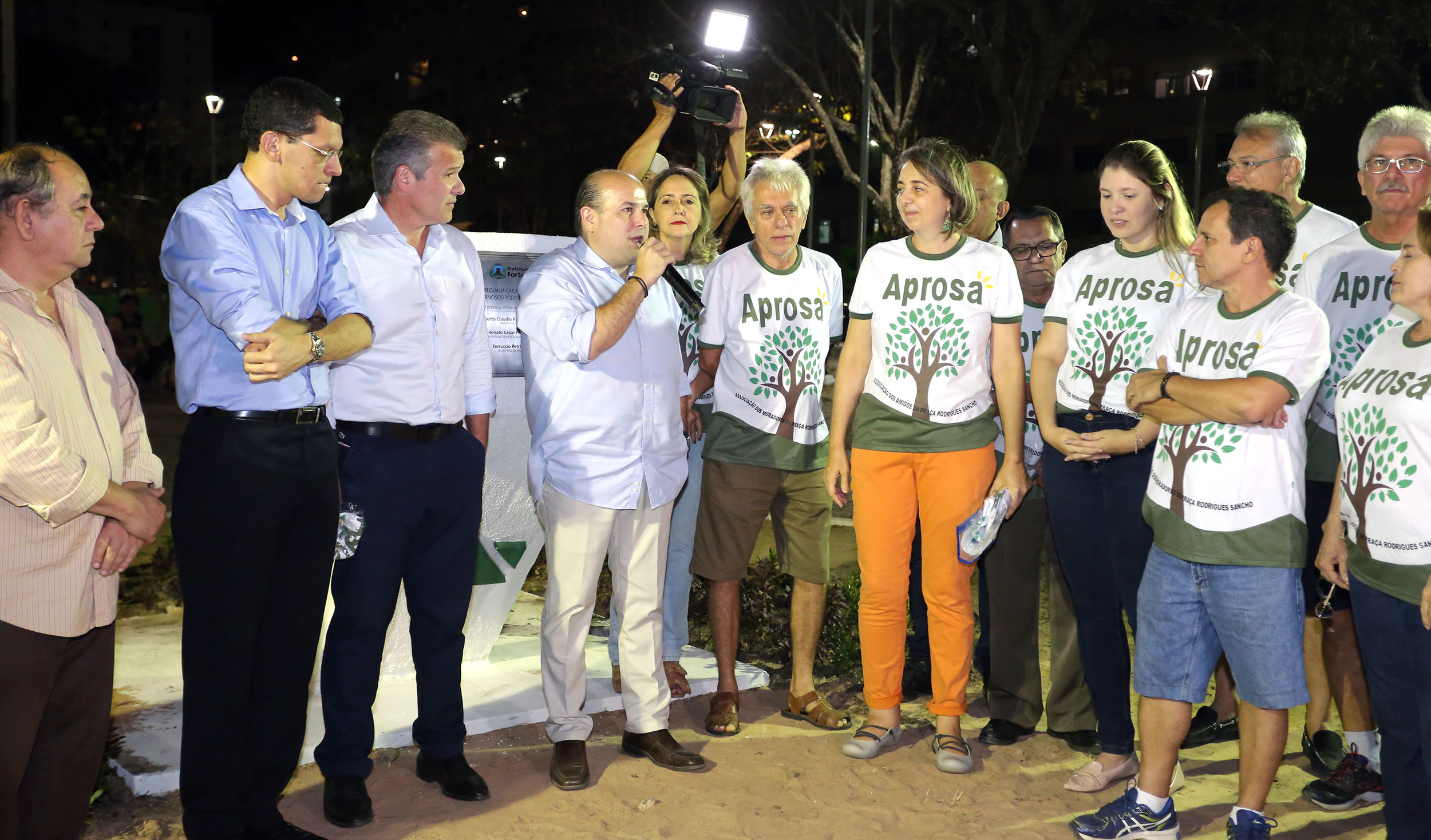 várias pessoas em pé na frente de uma placa de inauguração